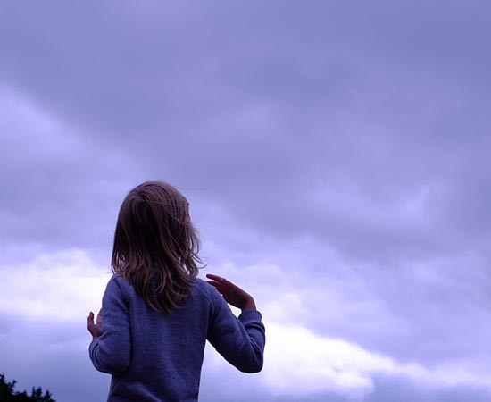 Ein Mädchen beobachtet die Wolken