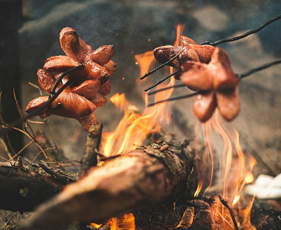Über dem Lagerfeuer Würste grillieren