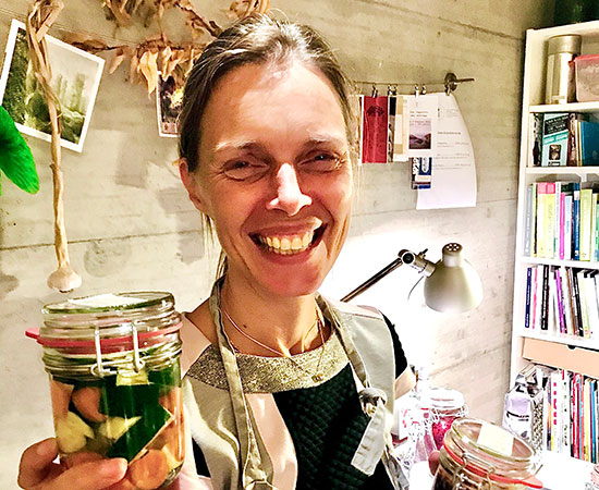 a woman holds a jar with vegetables