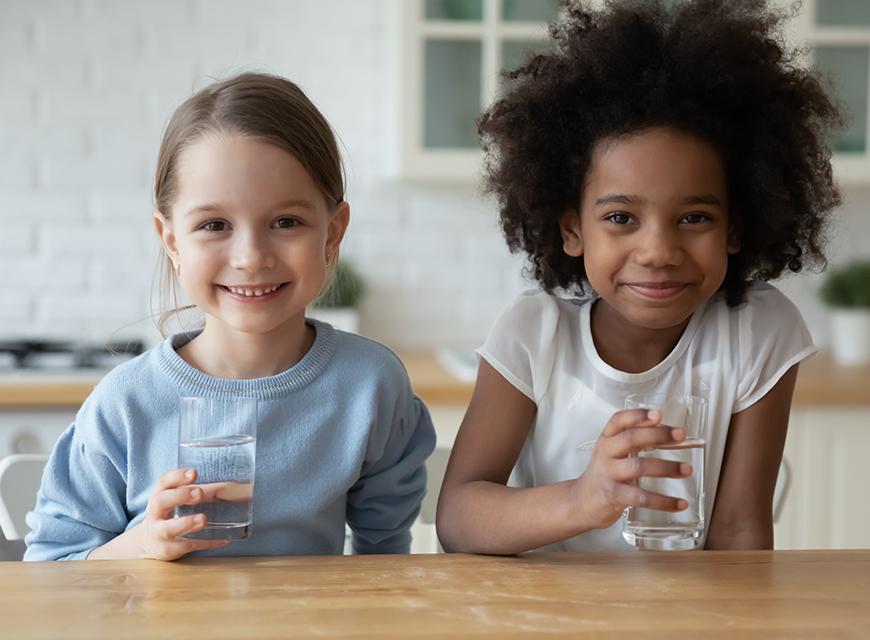Kinder erfrischen sich mit Schweizer Mineralwasser